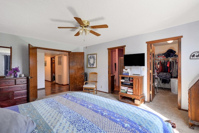 carpeted bedroom featuring a walk in closet, ceiling fan, and a closet