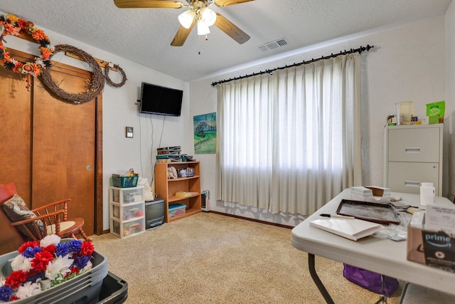 home office with ceiling fan, carpet floors, and a textured ceiling