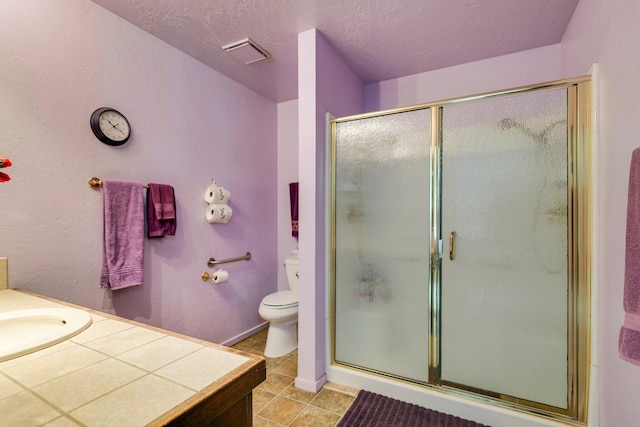 bathroom featuring vanity, a textured ceiling, a shower with shower door, tile patterned floors, and toilet