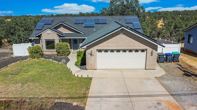 view of front of home featuring a garage, a front yard, and solar panels