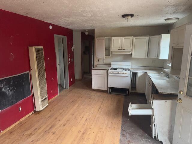 kitchen with white cabinets, sink, gas range gas stove, and light wood-type flooring