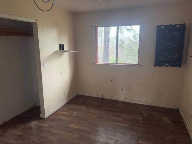 unfurnished bedroom featuring dark wood-type flooring and a textured ceiling