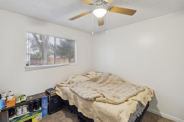 carpeted bedroom featuring ceiling fan and a textured ceiling