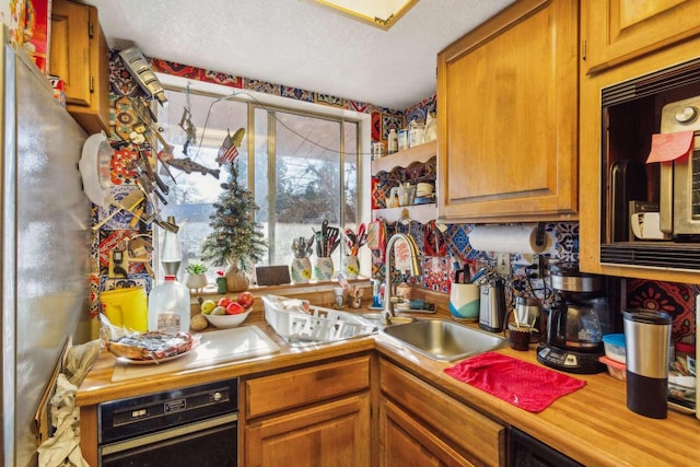 kitchen with black microwave, sink, oven, and a textured ceiling