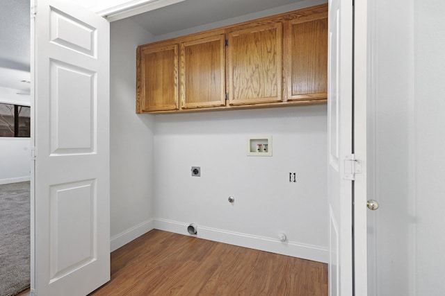 clothes washing area featuring gas dryer hookup, cabinets, washer hookup, light hardwood / wood-style floors, and hookup for an electric dryer