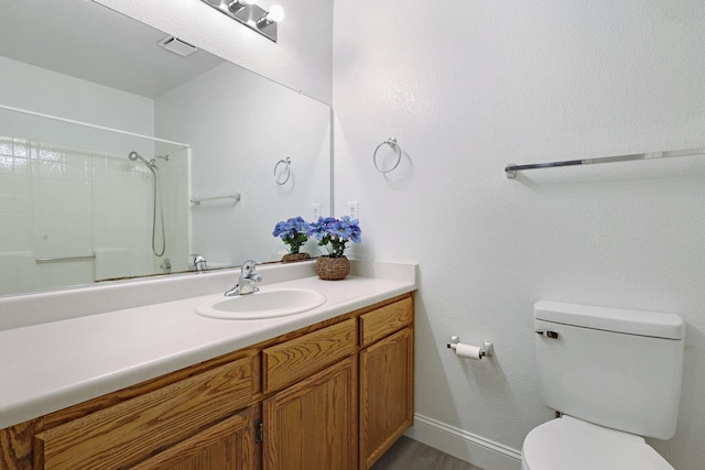 bathroom featuring vanity, a shower, and toilet