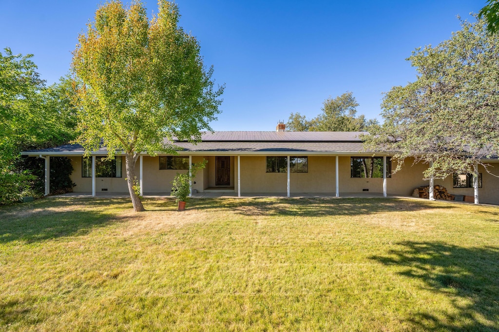 back of property with a yard and solar panels