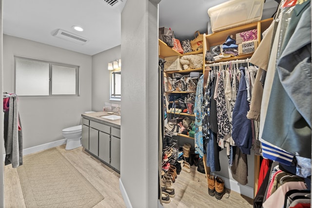 spacious closet with light wood finished floors, visible vents, and a sink