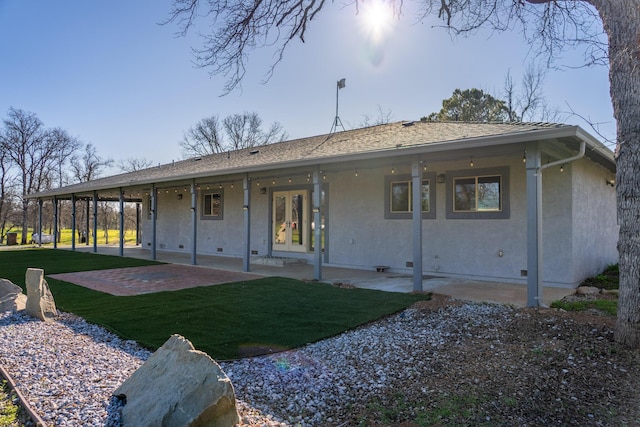 back of property with french doors, stucco siding, a shingled roof, a lawn, and a patio area