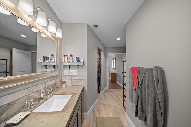 bathroom with tasteful backsplash, visible vents, baseboards, wood finished floors, and vanity