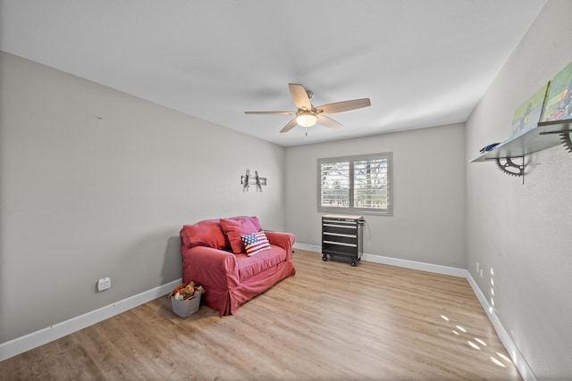 living area with a ceiling fan, baseboards, and wood finished floors