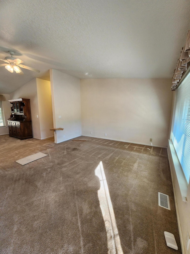 unfurnished living room featuring ceiling fan, lofted ceiling, carpet, and a textured ceiling