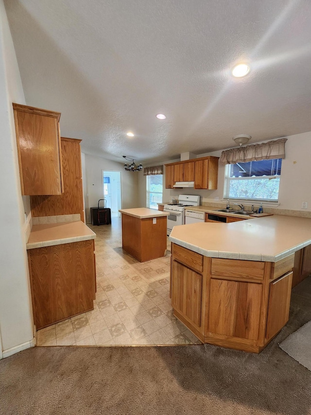 kitchen with a kitchen island, kitchen peninsula, light colored carpet, gas range gas stove, and a textured ceiling