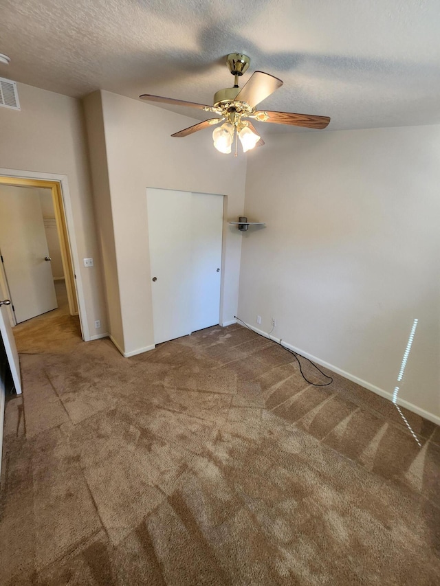 unfurnished bedroom featuring ceiling fan, a textured ceiling, and carpet flooring