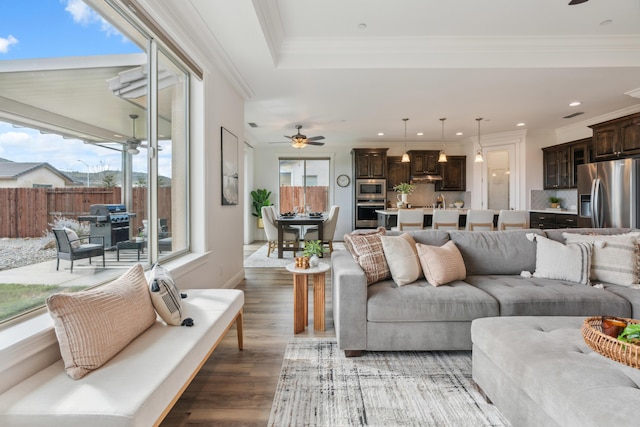 living room with crown molding, wood-type flooring, and ceiling fan