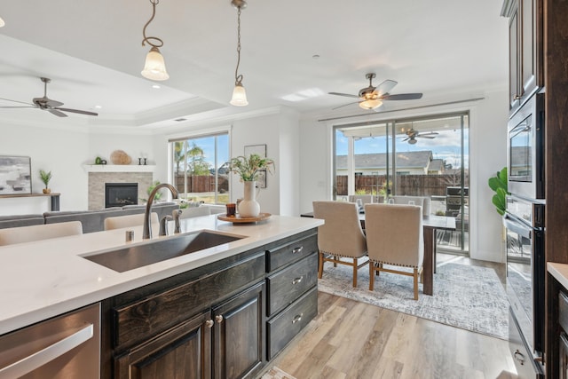 kitchen featuring sink, crown molding, appliances with stainless steel finishes, hanging light fixtures, and dark brown cabinetry