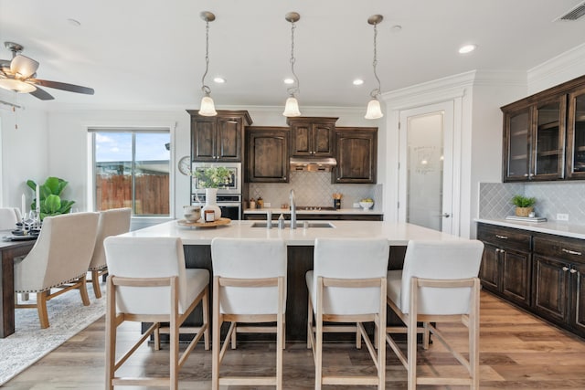 kitchen featuring sink, dark brown cabinets, an island with sink, and appliances with stainless steel finishes