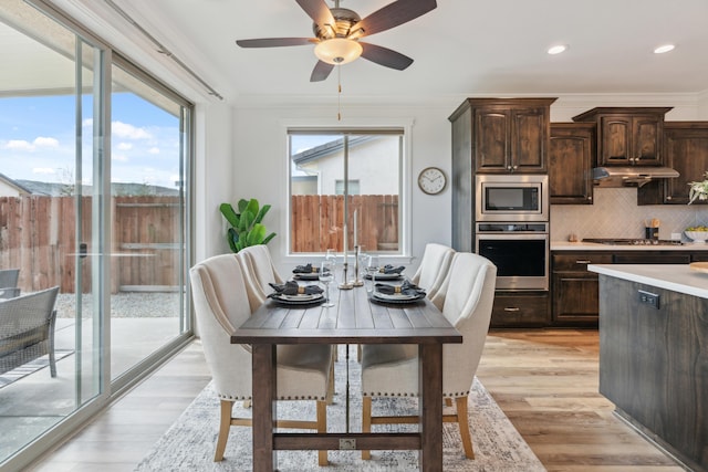 kitchen with backsplash, dark brown cabinets, stainless steel appliances, ornamental molding, and light wood-type flooring