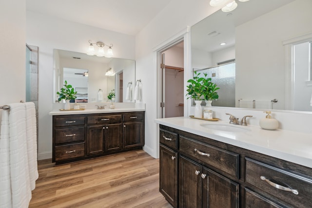 bathroom with hardwood / wood-style flooring, ceiling fan, vanity, and a shower