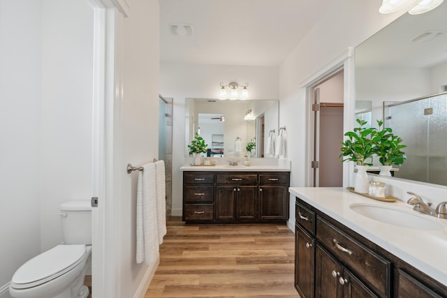 bathroom featuring vanity, toilet, an enclosed shower, and hardwood / wood-style floors