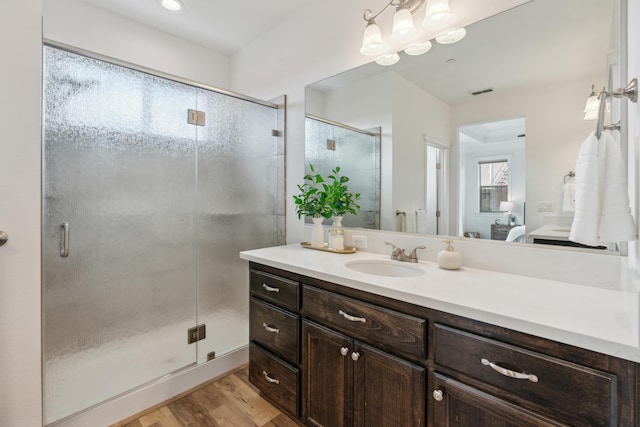 bathroom with hardwood / wood-style flooring, vanity, and a shower with door