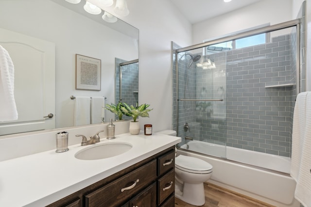 full bathroom featuring enclosed tub / shower combo, wood-type flooring, vanity, and toilet