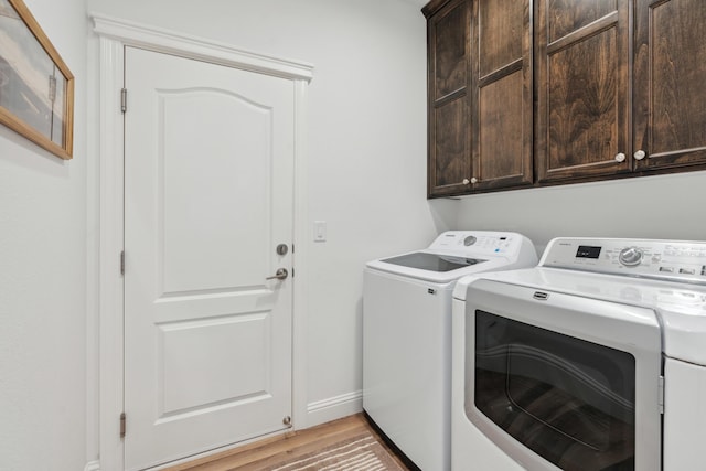 laundry room with cabinets, washing machine and clothes dryer, and light hardwood / wood-style flooring