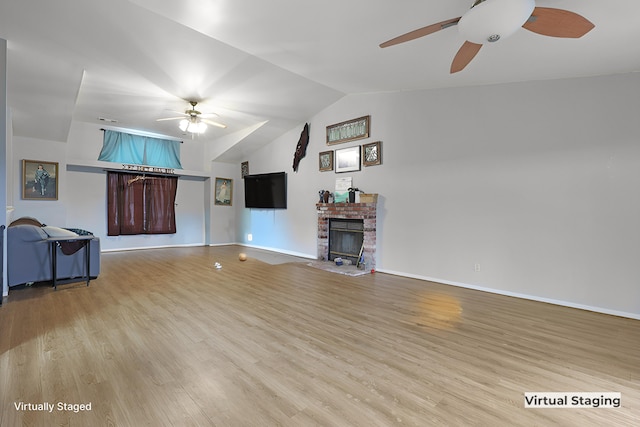 unfurnished living room with ceiling fan, vaulted ceiling, a brick fireplace, and light hardwood / wood-style flooring