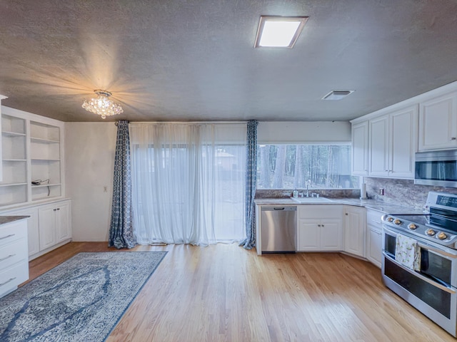 kitchen with stainless steel appliances, white cabinets, and a textured ceiling