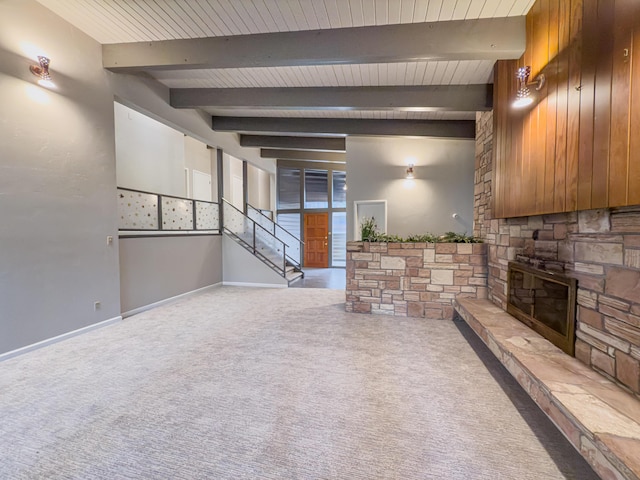 unfurnished living room with a stone fireplace, beam ceiling, carpet, and wooden ceiling