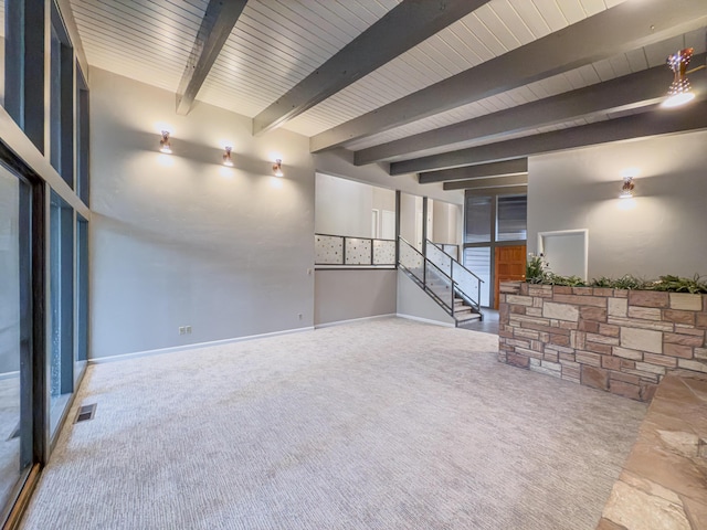 unfurnished living room featuring beamed ceiling, carpet, and wood ceiling