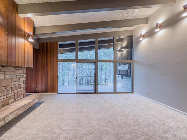 unfurnished living room with wooden walls, beam ceiling, and carpet