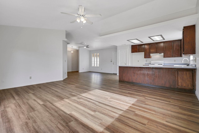 kitchen featuring sink, ceiling fan, stove, kitchen peninsula, and light wood-type flooring