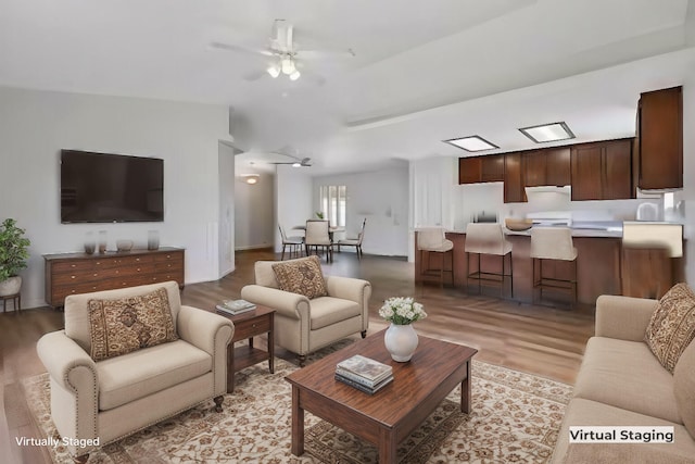 living room featuring ceiling fan, lofted ceiling, and light hardwood / wood-style floors