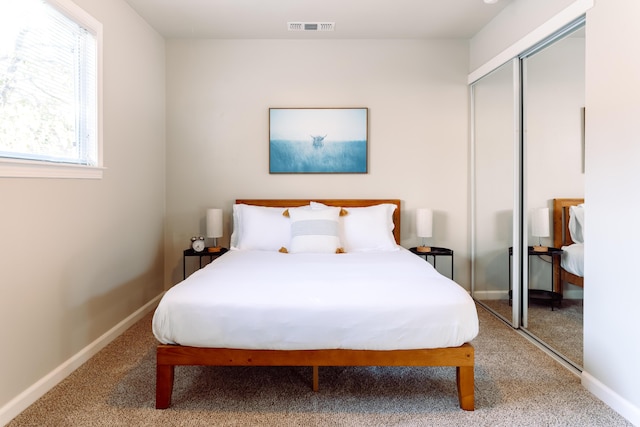 bedroom with carpet floors, a closet, visible vents, and baseboards