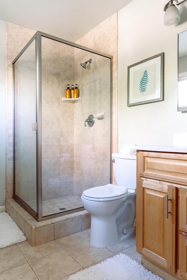 bathroom with toilet, a shower stall, tile patterned flooring, and vanity