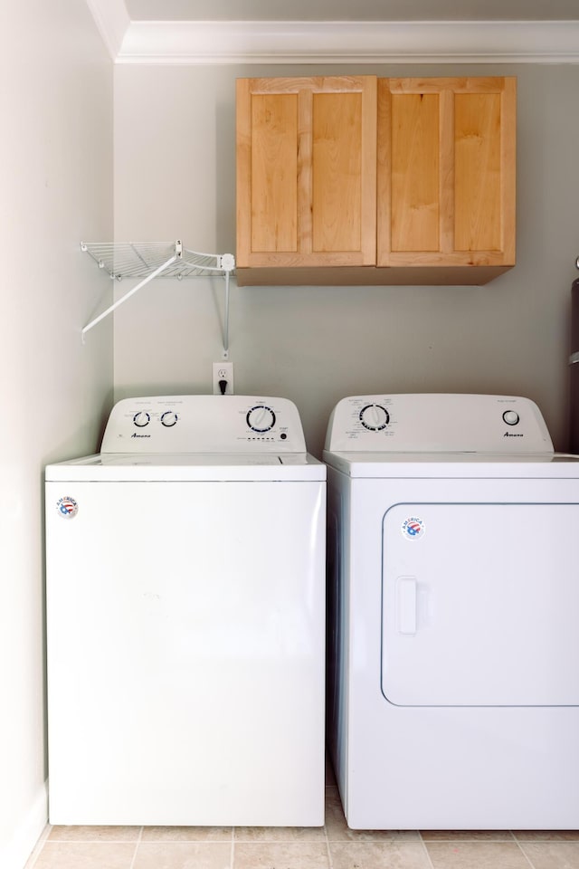 laundry area featuring cabinet space, crown molding, and washing machine and clothes dryer