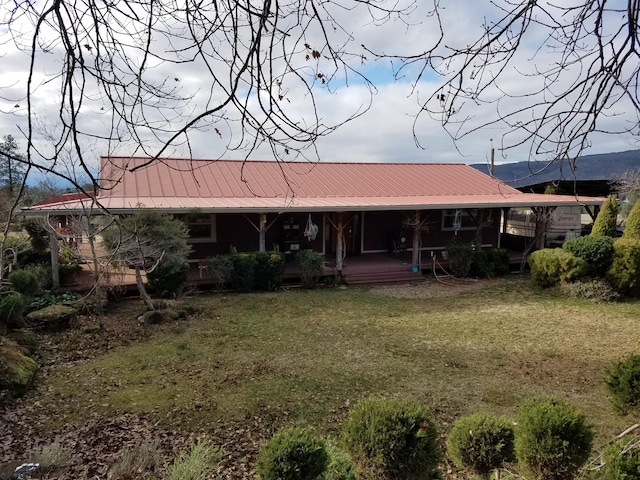 back of house featuring a porch, a yard, and metal roof