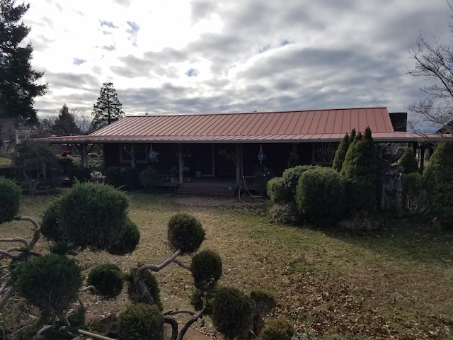 rear view of house featuring a yard, a standing seam roof, and metal roof