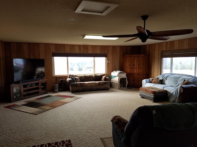 carpeted living area with wooden walls, a textured ceiling, and ceiling fan