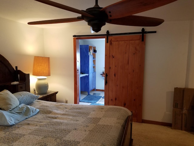 bedroom featuring a barn door, light carpet, and ensuite bathroom