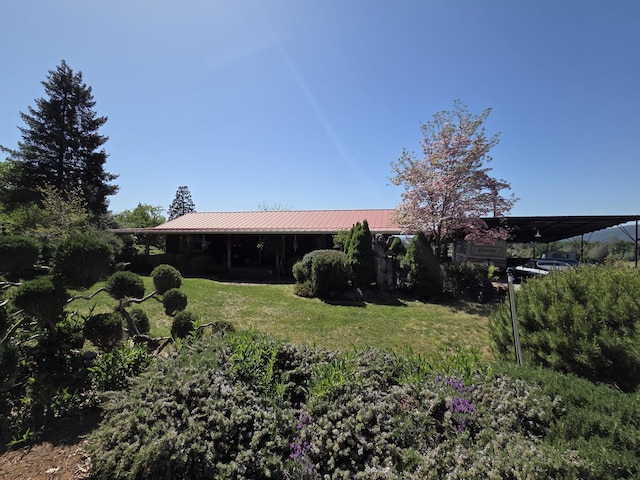 rear view of property featuring a yard and metal roof