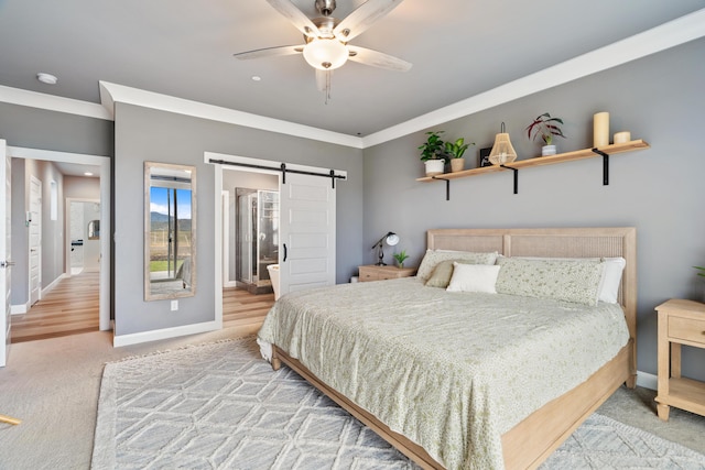 bedroom featuring connected bathroom, ornamental molding, carpet, ceiling fan, and a barn door