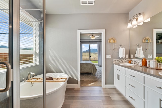 bathroom featuring vanity, a bath, hardwood / wood-style flooring, and ceiling fan