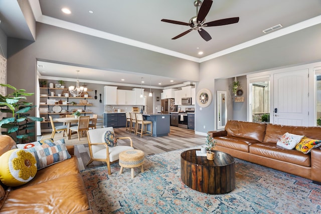 living room with crown molding, sink, ceiling fan with notable chandelier, and light hardwood / wood-style flooring