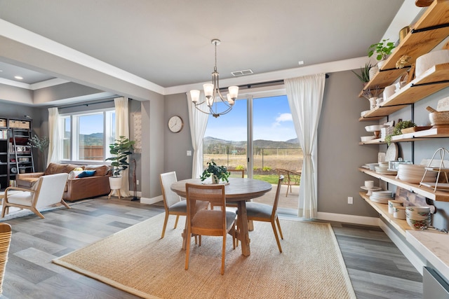 dining space with crown molding, a mountain view, a chandelier, and light hardwood / wood-style flooring