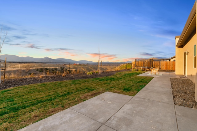 yard at dusk with a mountain view and a patio area