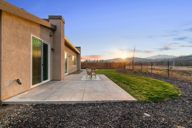 yard at dusk with a patio and a mountain view