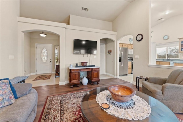 living room with sink, light hardwood / wood-style flooring, and high vaulted ceiling