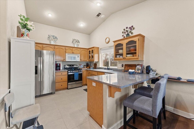 kitchen with sink, a breakfast bar area, appliances with stainless steel finishes, high vaulted ceiling, and kitchen peninsula